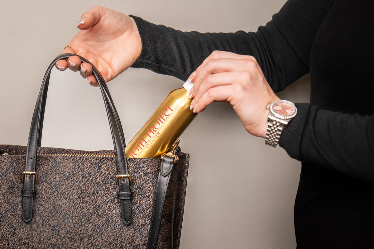 Applying Totel Protect leather cleaner to the side of a brown leather handbag with a cloth
