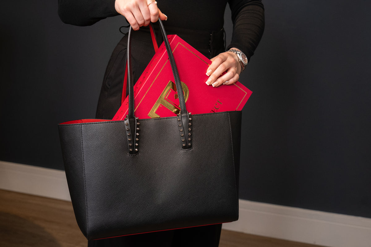 The Luxe Handbag Care Kit box being placed into a black leather tote
